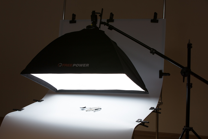Eine im Vergleich zu den kleinen Produkten relativ große Softbox erzeugt eine sich unter vielen verschiedenen Winkeln spiegelnde Lichtquelle. In dieser Szene wurde ein Fototisch benutzt, genauso gut hätte es aber auch mit einer Tischdecke als Unterlage funktioniert.