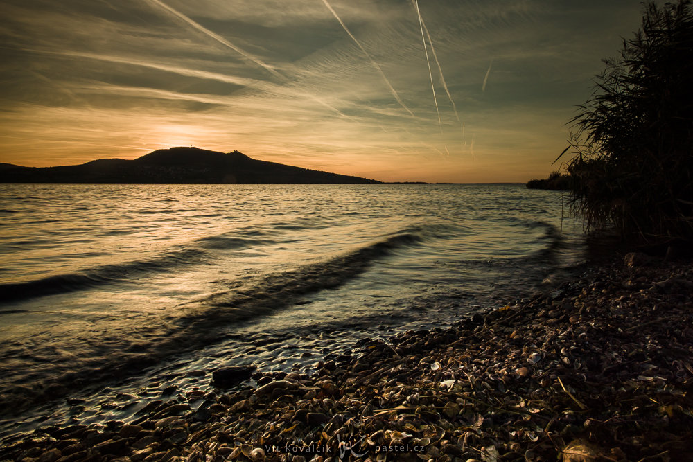 Ein See mit einem Hügel im Hintergrund.
