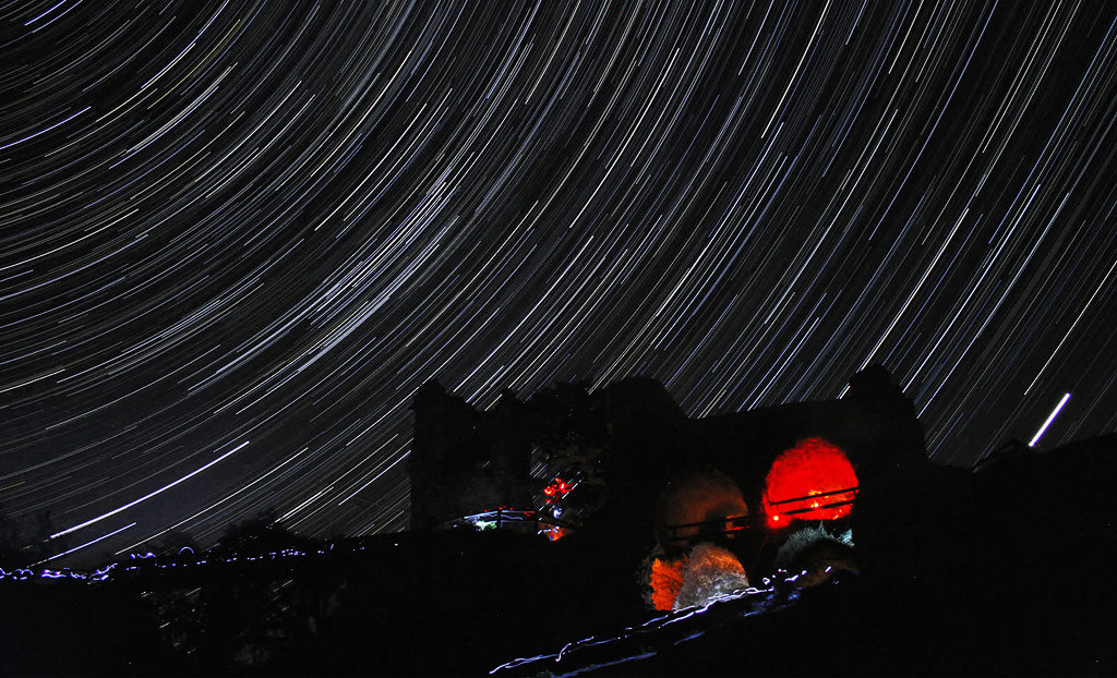 Beherrschen Sie das Fotografieren der Sternspuren. 5 Tipps, wie man Startrails fotografiert: Sternspuren über der Bergruine Zubštejn.