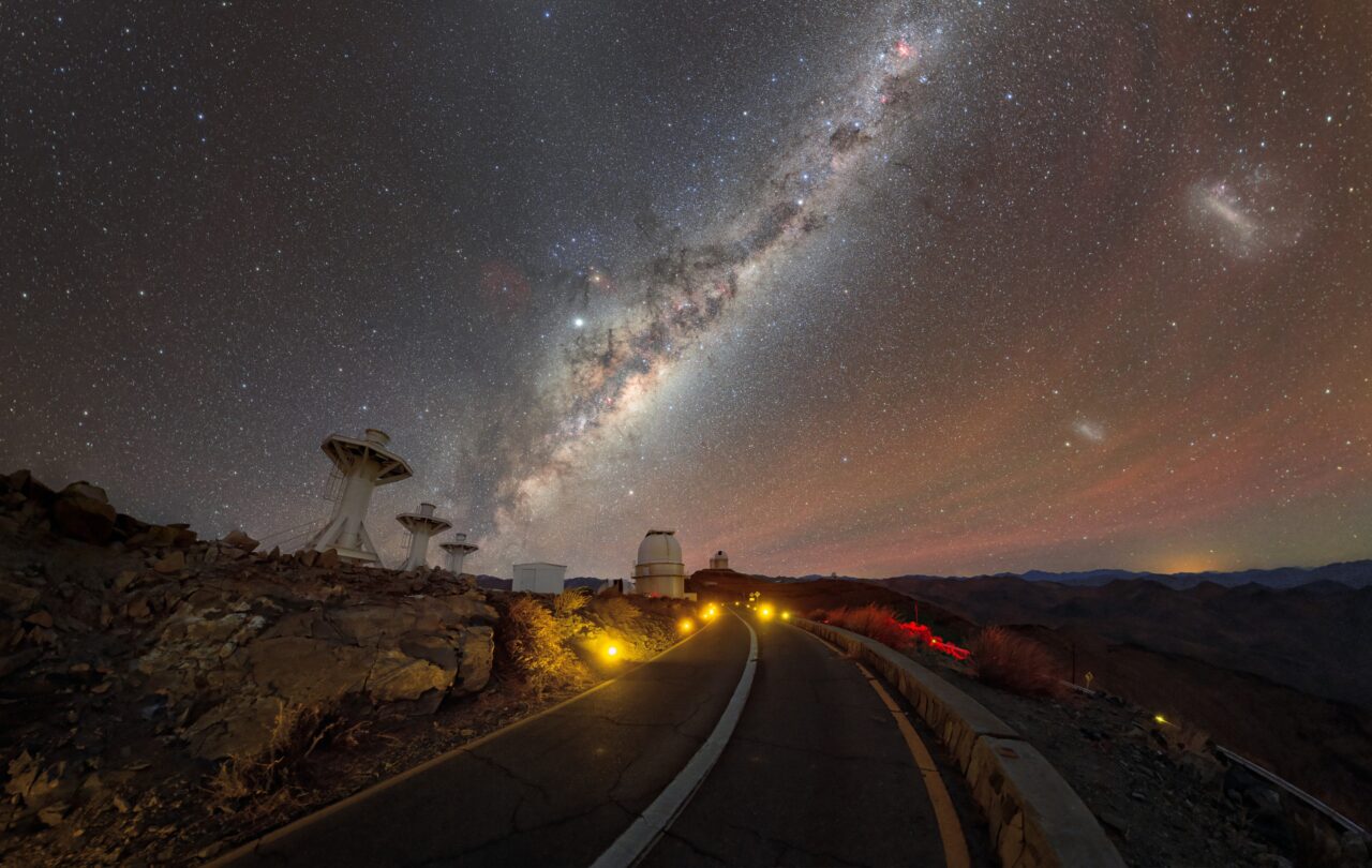 Interview Petr Horálek,Die majestätische Milchstraße über dem La Silla-Observatorium der ESO in Chile. Rechts daneben sind die Magellanschen Wolken und die roten Streifen der natürlichen Strahlung in der Erdatmosphäre zu sehen.